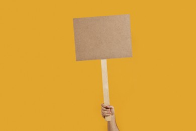 Photo of Man holding blank sign on orange background, closeup. Space for text