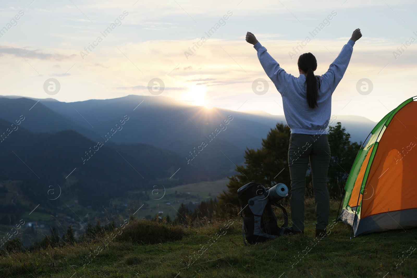 Photo of Tourist with backpack and sleeping pad near camping tent in mountains