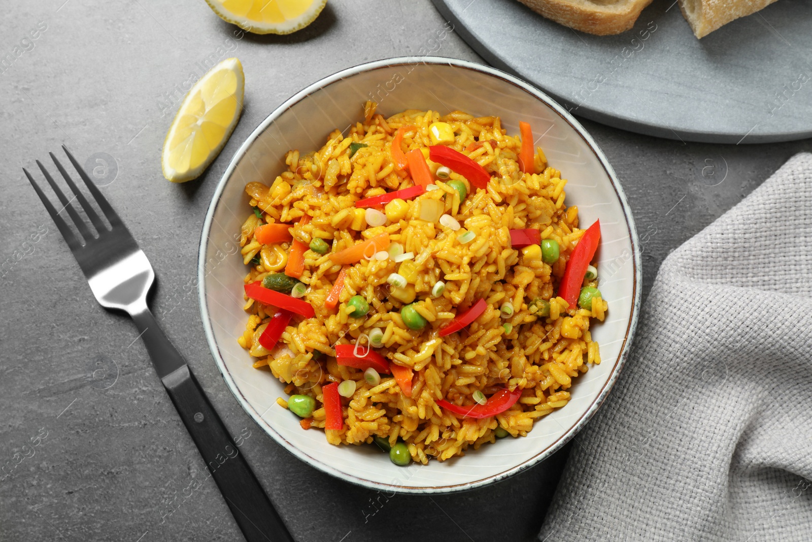 Photo of Delicious rice pilaf with vegetables on grey table, flat lay