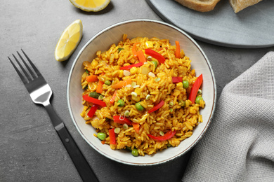 Delicious rice pilaf with vegetables on grey table, flat lay