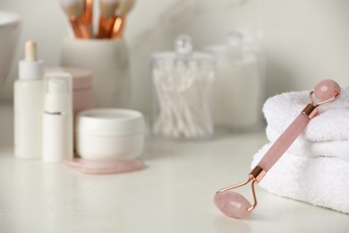 Photo of Natural face roller, gua sha tool and cosmetic products on counter in bathroom