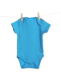 Photo of Baby onesie hanging on clothes line against white background. Laundry day