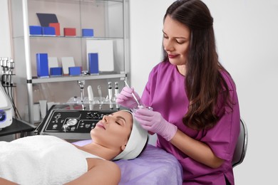 Photo of Young woman undergoing cosmetic procedure in beauty salon