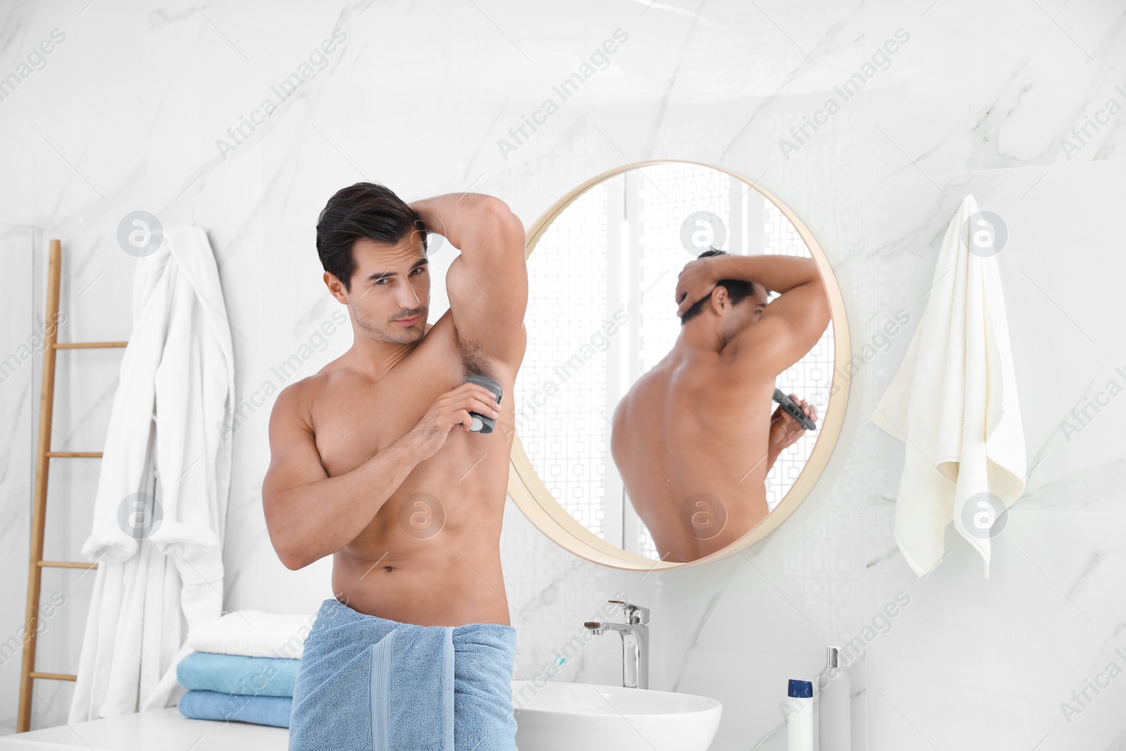 Photo of Handsome young man applying deodorant in bathroom