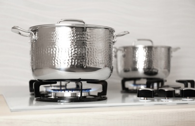 Photo of Shiny steel saucepans on modern gas stove