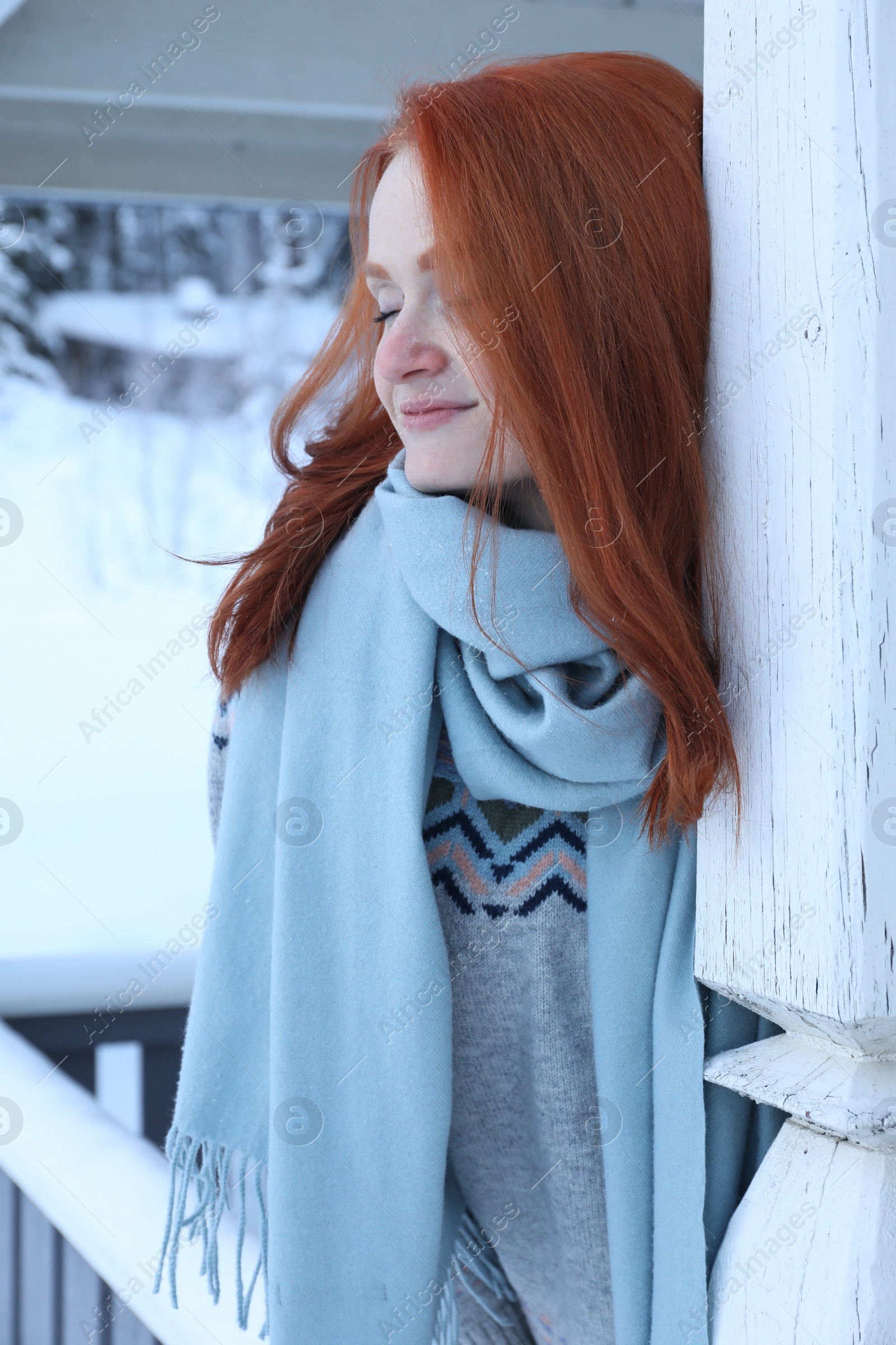 Photo of Beautiful young woman in wooden gazebo on snowy day outdoors. Winter vacation