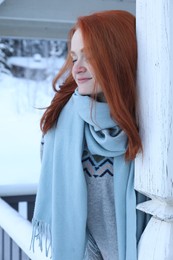 Photo of Beautiful young woman in wooden gazebo on snowy day outdoors. Winter vacation
