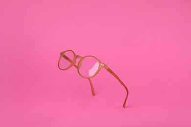 Photo of Glasses with corrective lenses on bright pink background