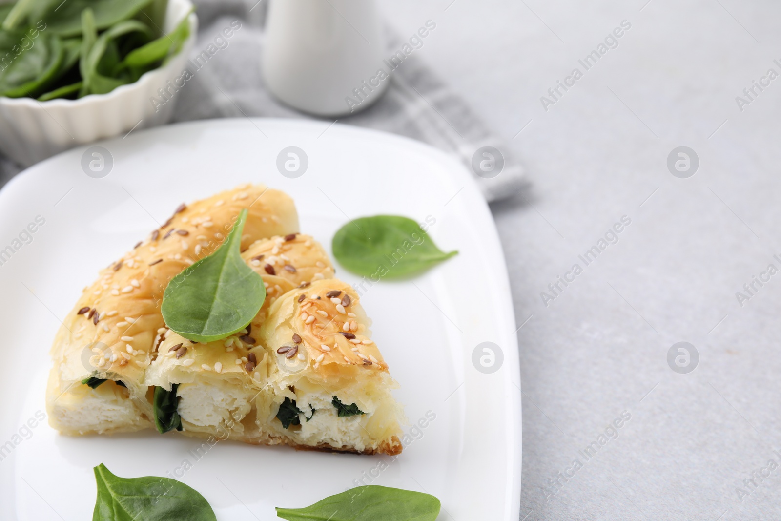 Photo of Piece of delicious puff pastry with spinach on light table, closeup