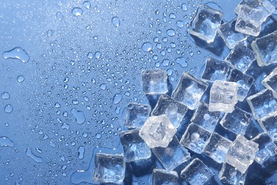 Photo of Melting ice cubes and water drops on blue background, flat lay. Space for text