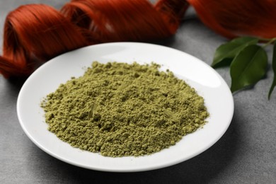 Photo of Henna powder and red strand on grey table, closeup. Natural hair coloring
