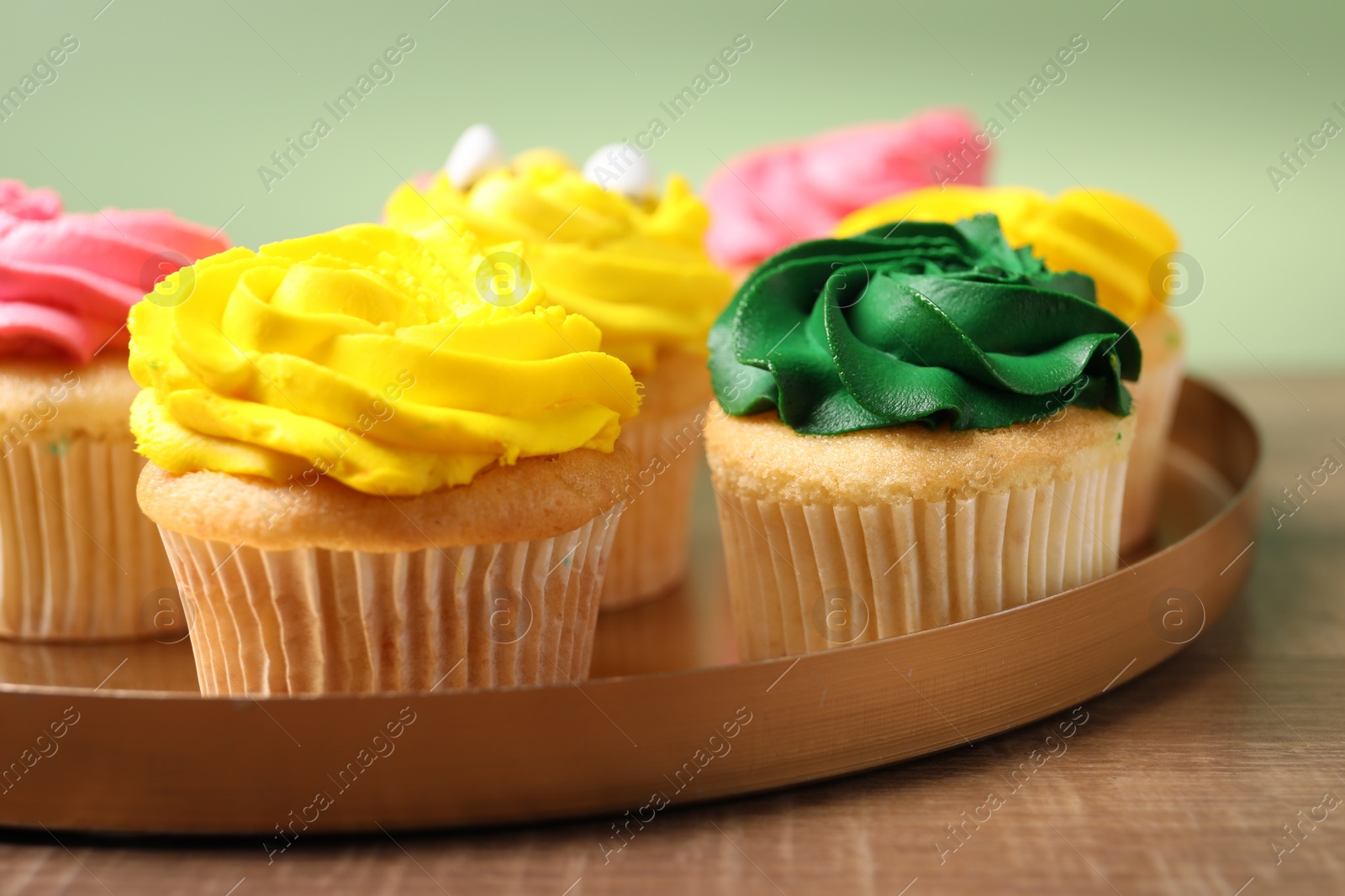 Photo of Delicious cupcakes with bright cream on wooden table, closeup