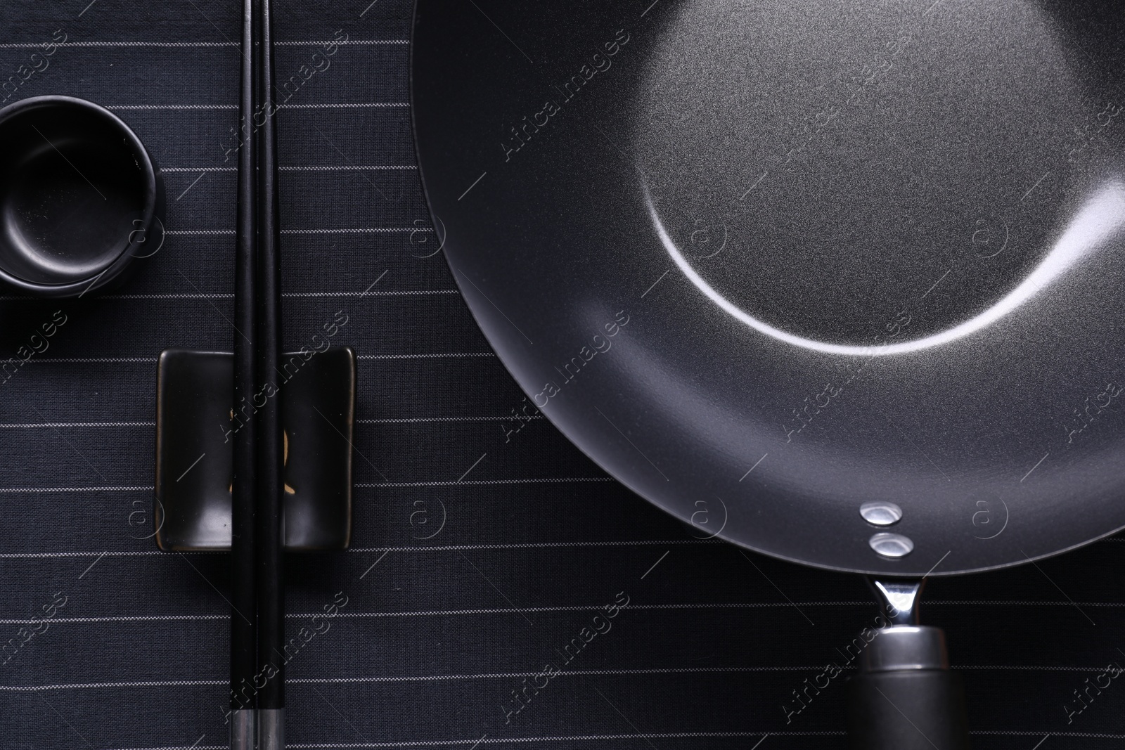Photo of Empty iron wok, sauce bowl and chopsticks on table, flat lay
