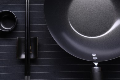 Photo of Empty iron wok, sauce bowl and chopsticks on table, flat lay