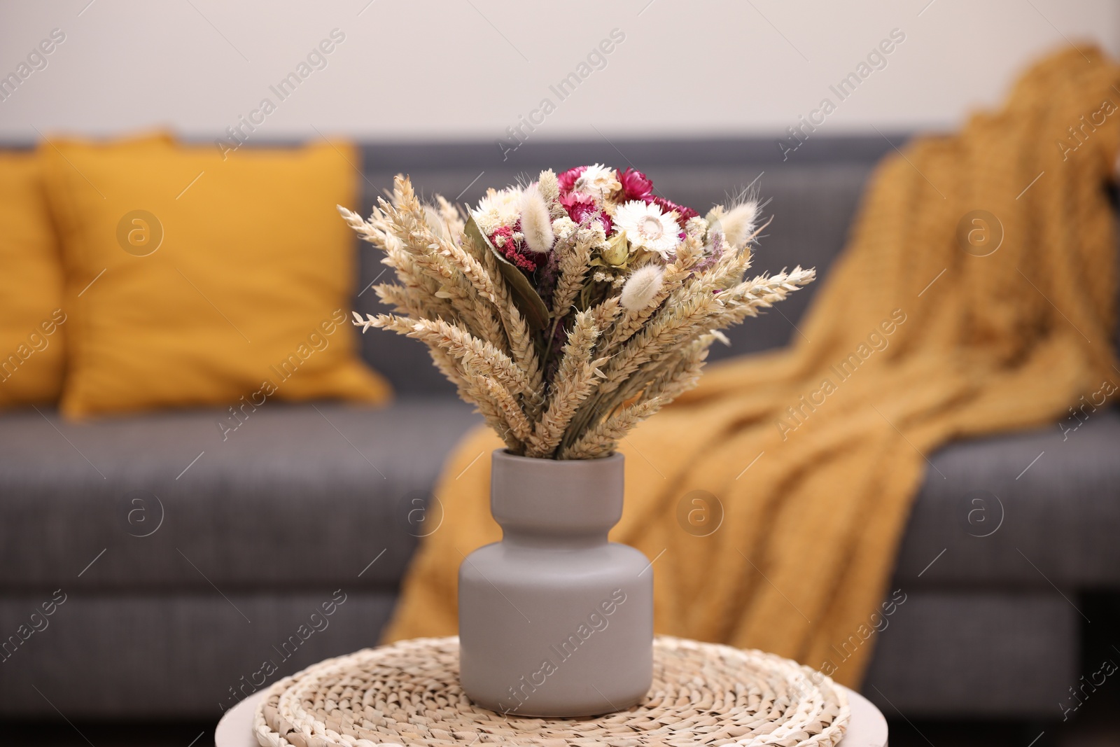 Photo of Bouquet of beautiful dry flowers and spikelets in vase on side table at home