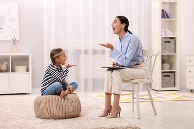 Photo of Dyslexia treatment. Speech therapist working with girl in room