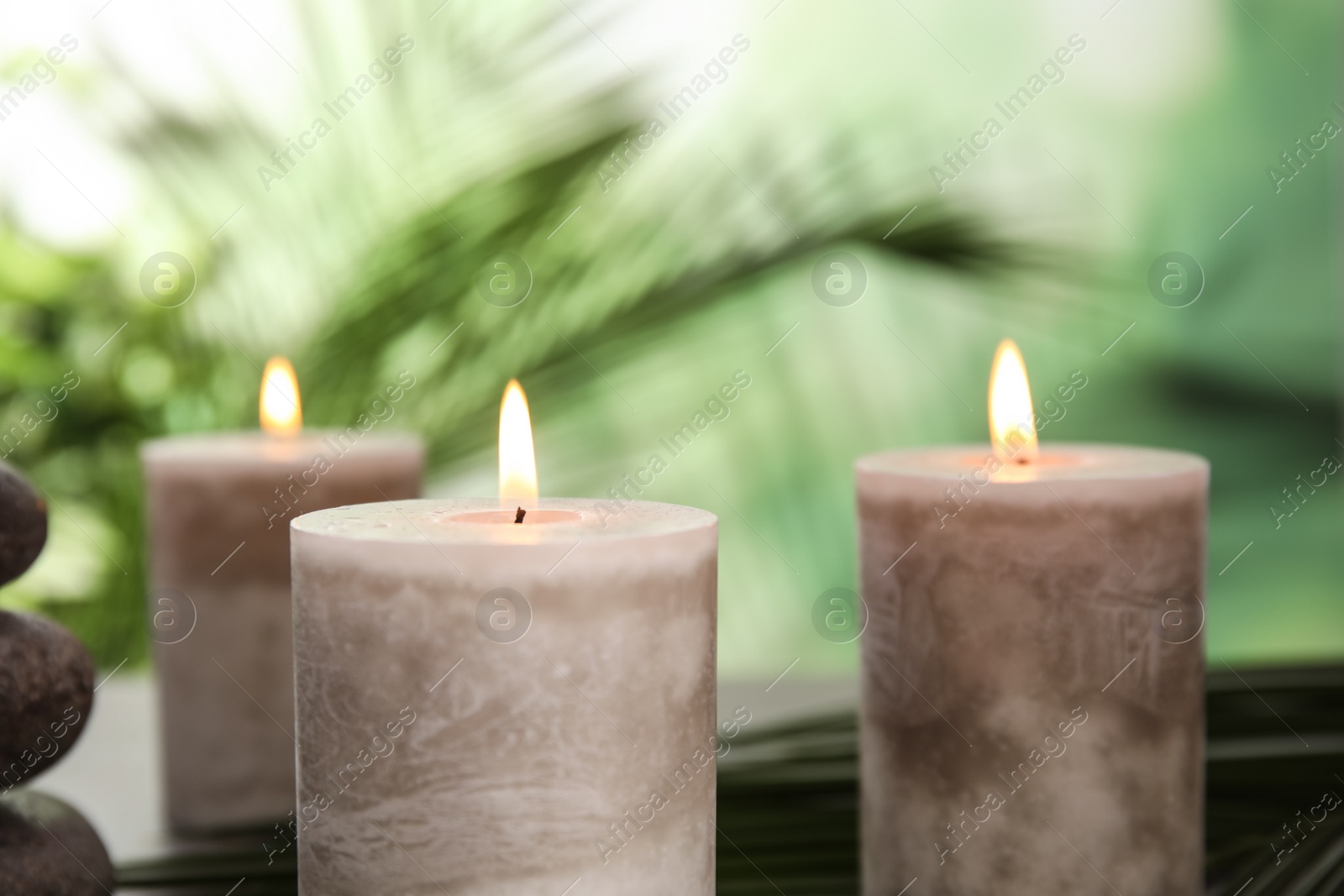 Photo of Burning aromatic candles on blurred green background