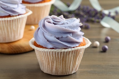 Photo of Tasty cupcake with cream on wooden table, closeup