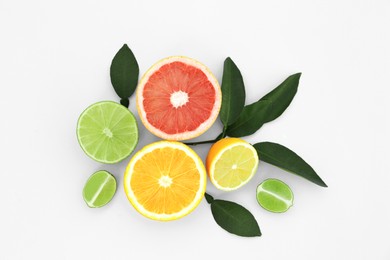 Different citrus fruits and leaves on white background, top view