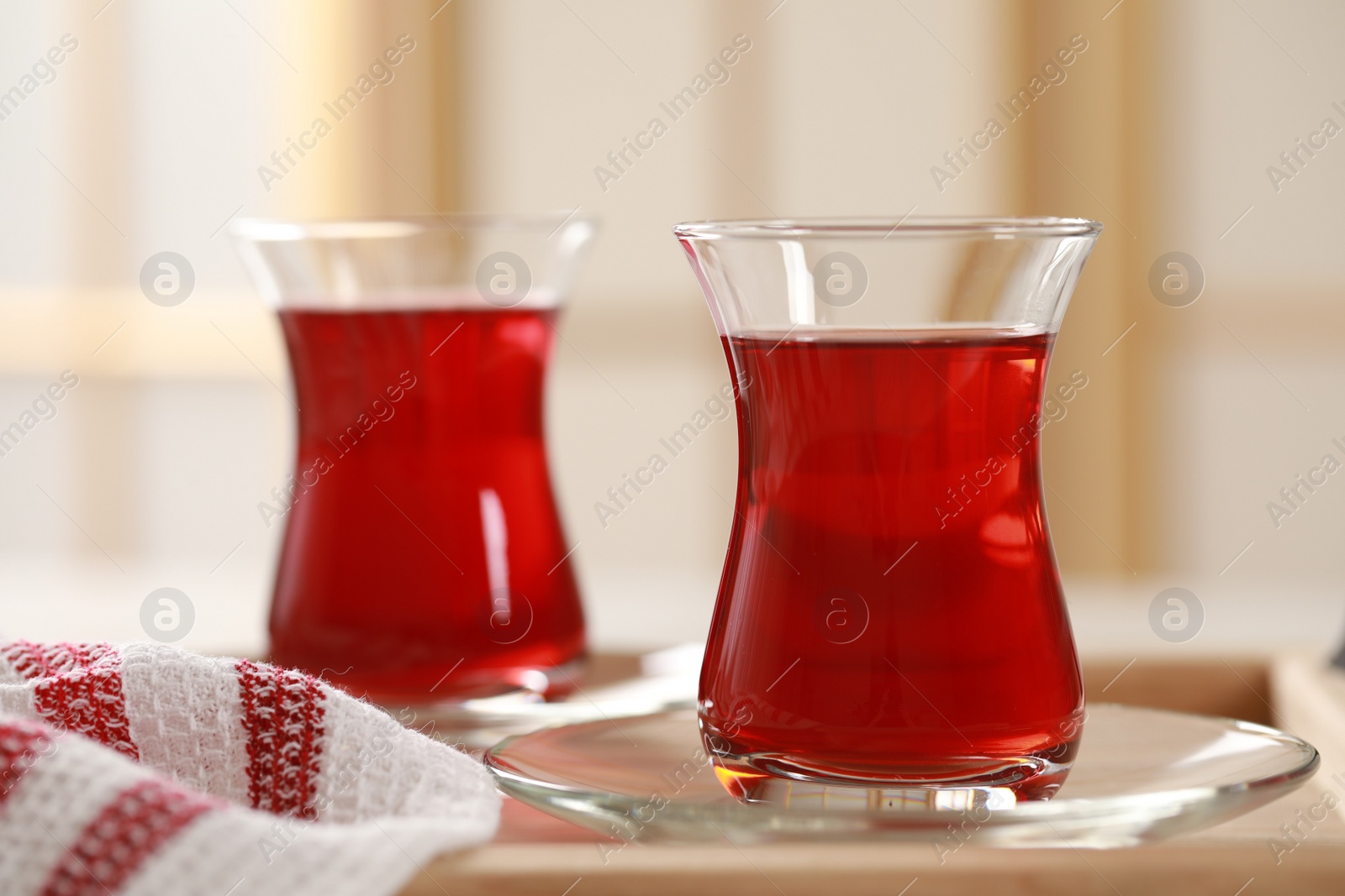 Photo of Glasses of traditional Turkish tea on wooden tray, closeup