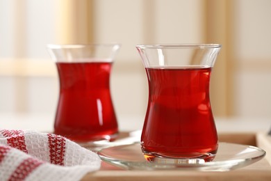 Photo of Glasses of traditional Turkish tea on wooden tray, closeup