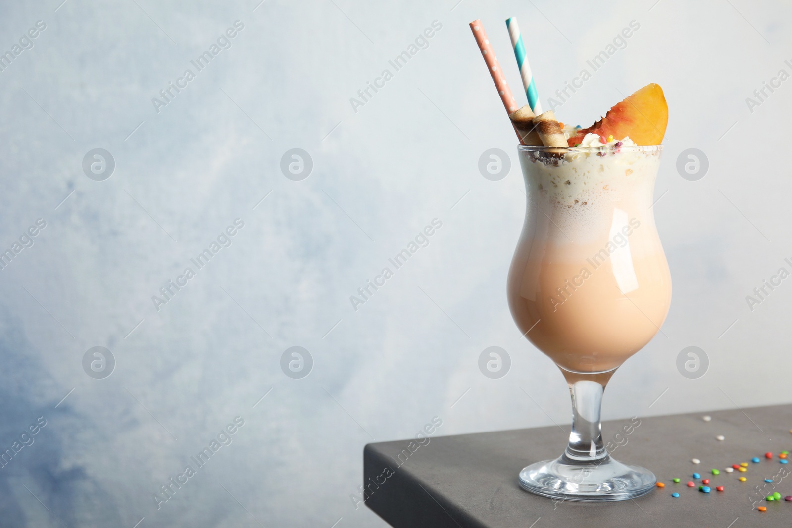 Photo of Glass with delicious milk shake on table against color background. Space for text