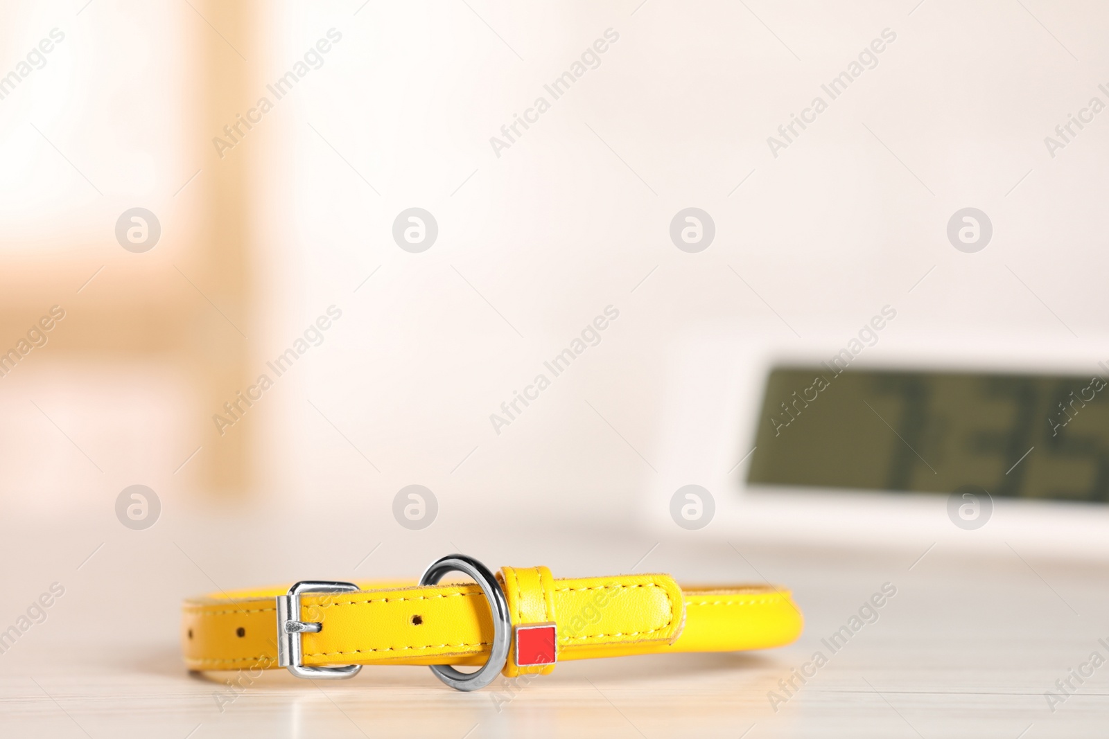 Photo of Yellow leather dog collar on table against blurred background, space for text