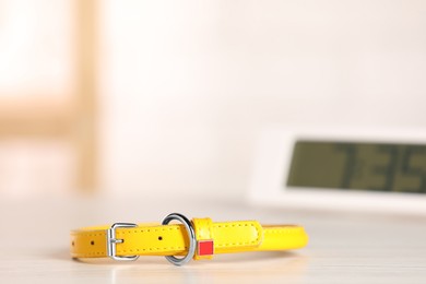 Photo of Yellow leather dog collar on table against blurred background, space for text