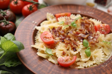 Tasty pasta with bacon, tomatoes and basil on table, closeup