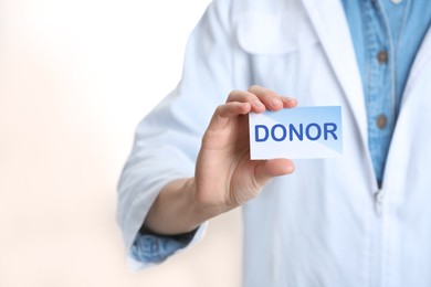 Image of Doctor holding card with word DONOR on white background, closeup