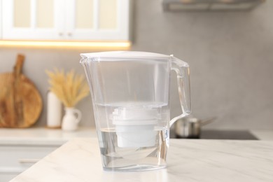 Water filter jug on white marble table in kitchen