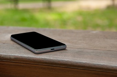 Photo of Smartphone on wooden bench outdoors, space for text. Lost and found