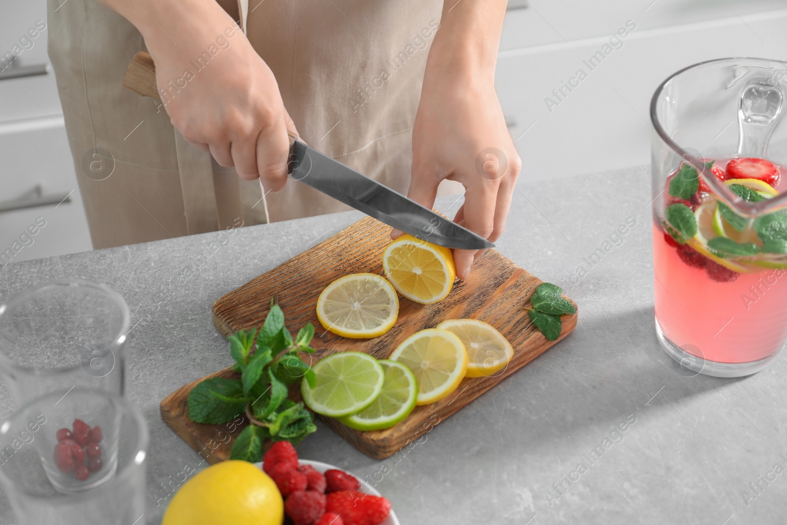 Photo of Woman preparing fresh lemonade on table