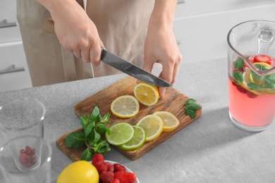 Woman preparing fresh lemonade on table