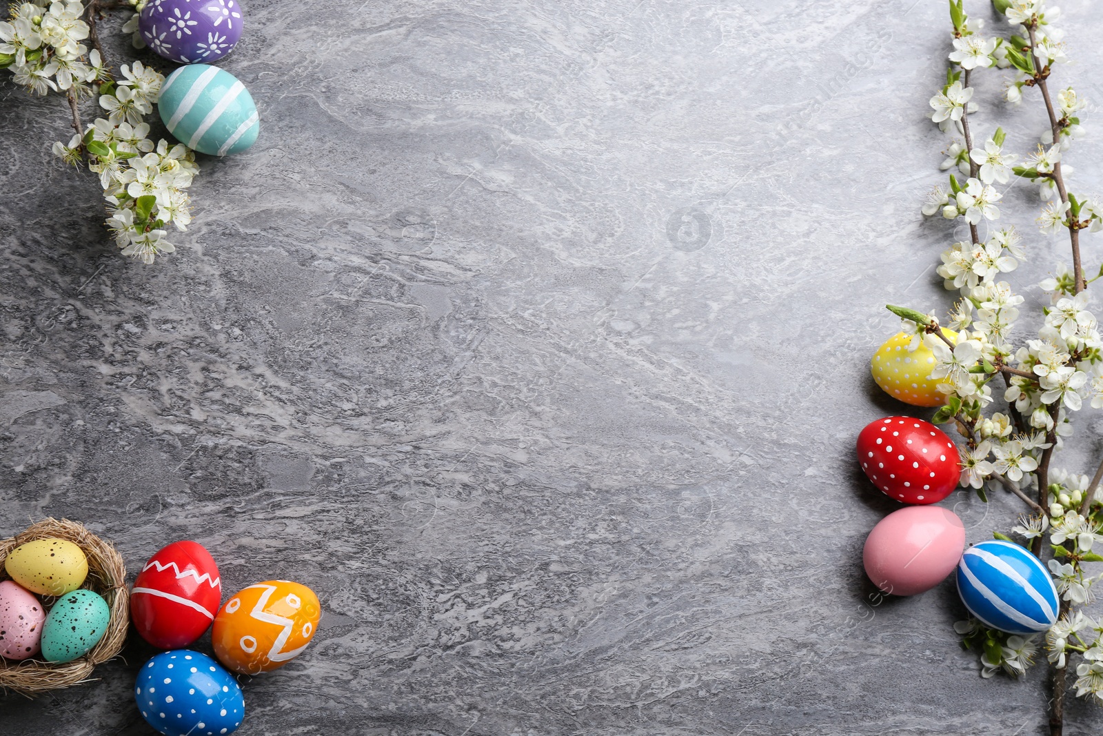 Photo of Flat lay composition with painted Easter eggs and blossoming branches on color background. Space for text