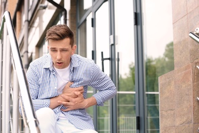 Photo of Young man having chest pain outdoors. Heart attack