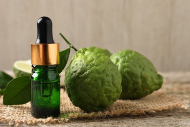 Photo of Bottle of essential oil and fresh bergamot fruits on table