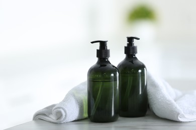 Photo of Soap dispensers and clean towel on white table