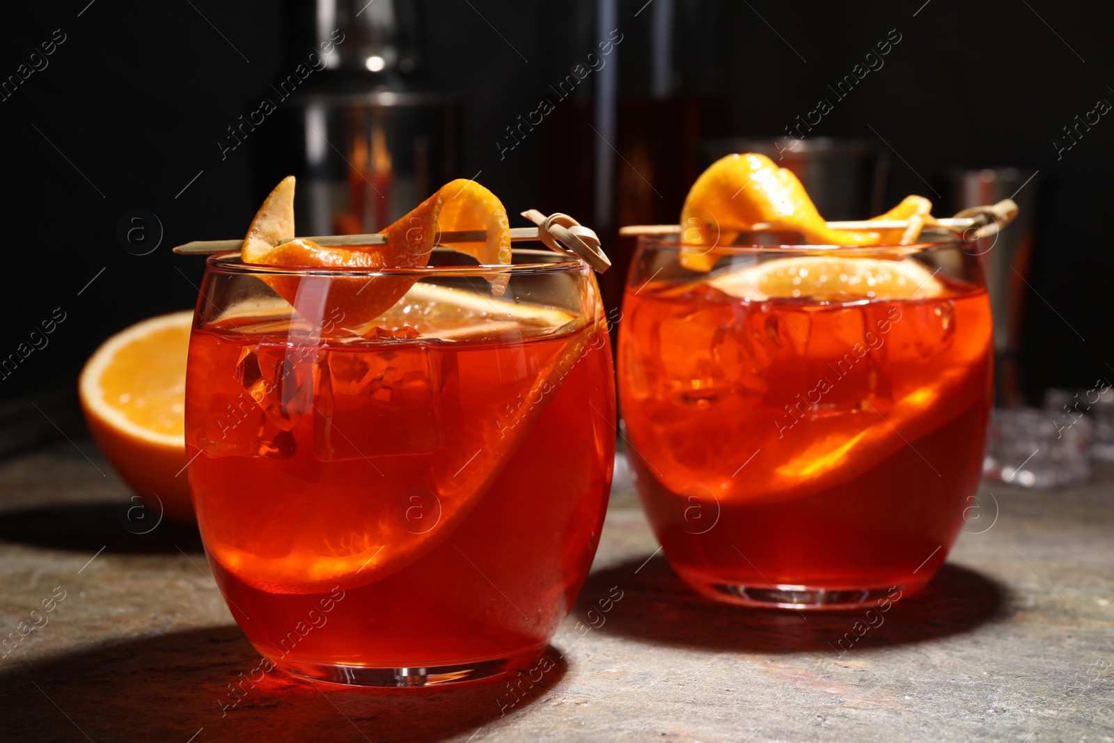 Photo of Aperol spritz cocktail, ice cubes and orange slices in glasses on grey textured table, closeup