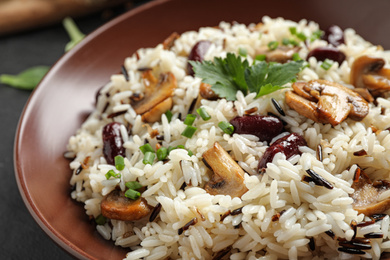 Photo of Delicious rice pilaf with mushrooms and beans in plate, closeup