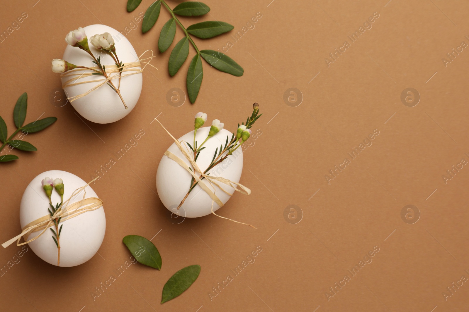 Photo of Happy Easter. Festive composition with eggs and floral decor on brown background, flat lay. Space for text.