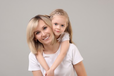 Family portrait of happy mother and daughter on grey background