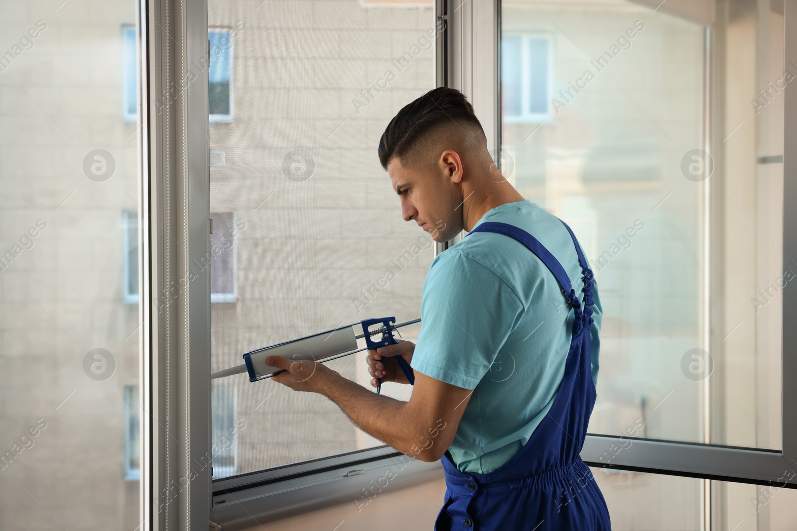 Photo of Construction worker sealing window with caulk indoors