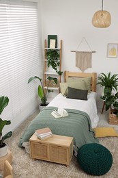 Large comfortable bed and potted houseplants in stylish bedroom. Interior design