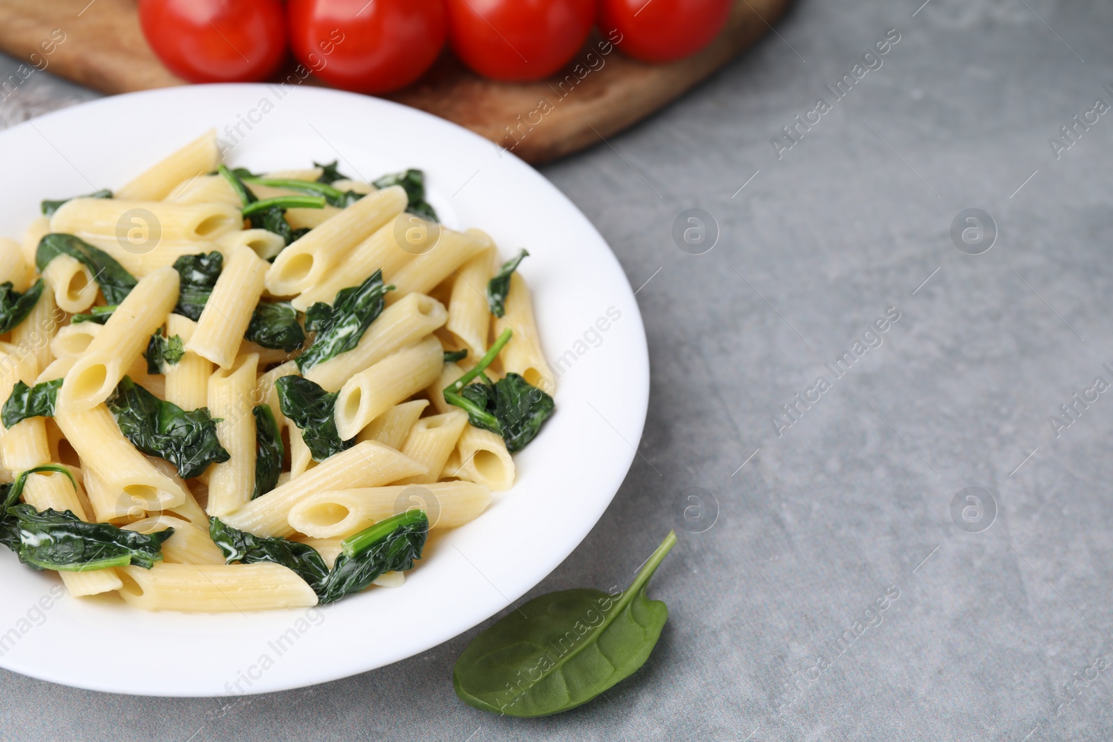 Photo of Tasty pasta with spinach and sauce on grey table, space for text