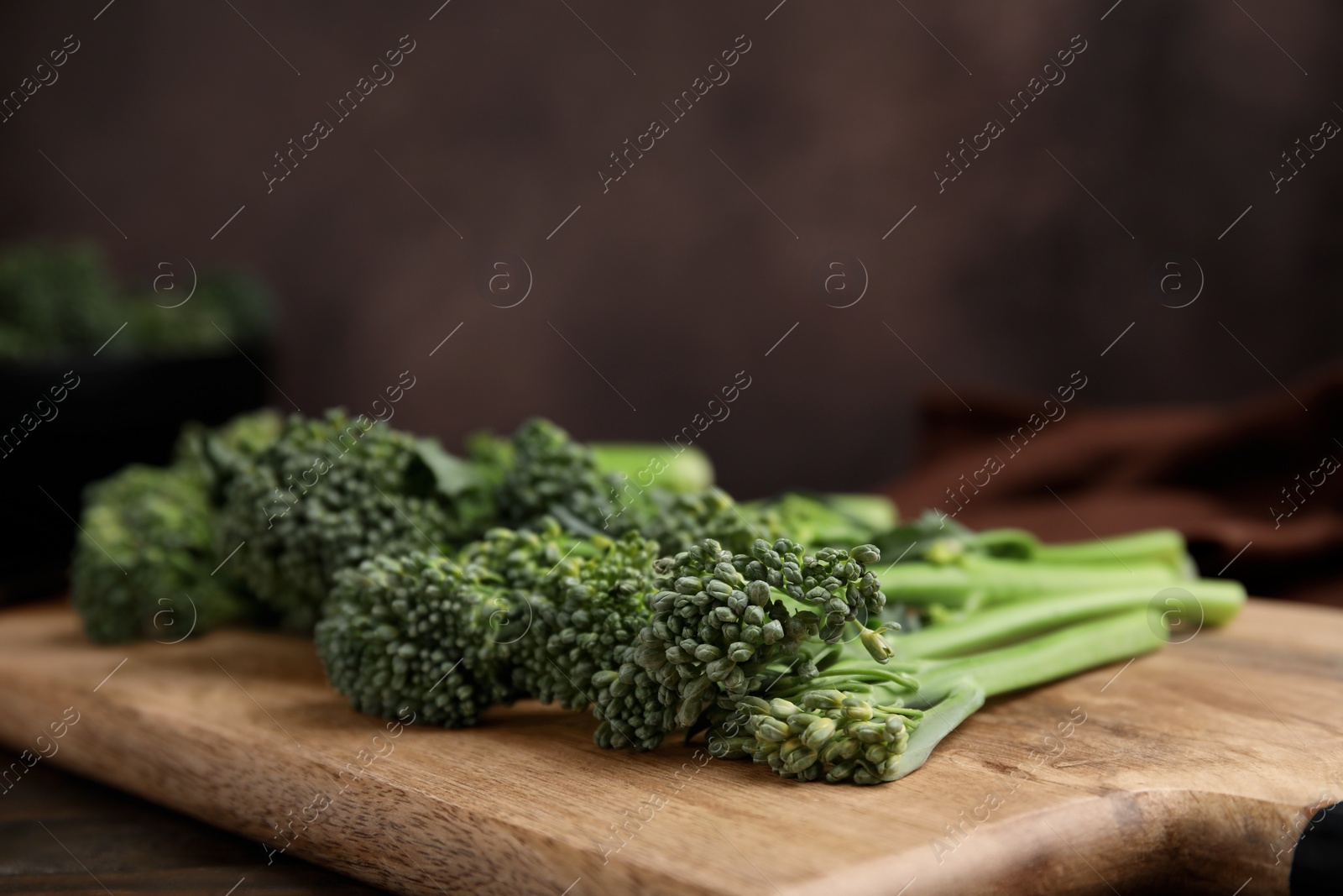 Photo of Fresh raw broccolini on wooden board, closeup. Healthy food