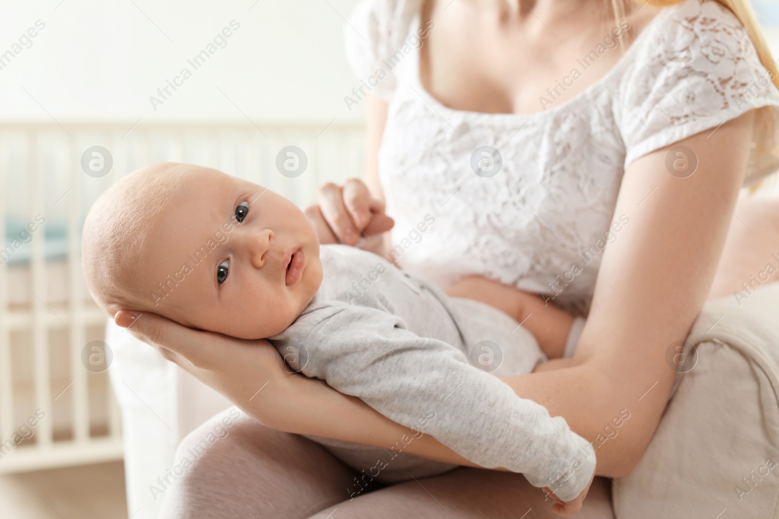 Photo of Mother with her baby sitting in armchair at home