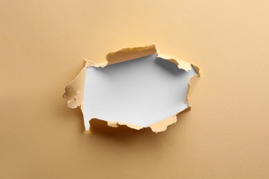 Hole in light beige paper on white background