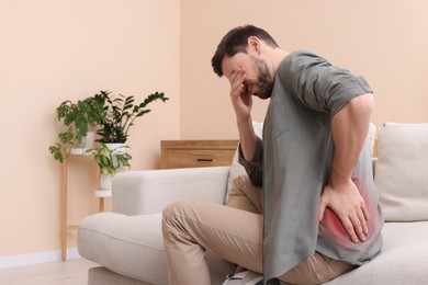 Image of Man suffering from back pain on sofa at home