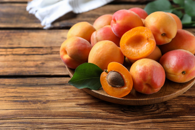 Photo of Delicious fresh ripe apricots on wooden table